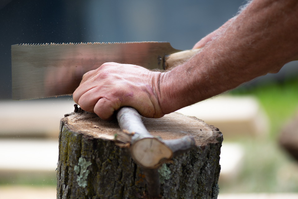 Mans hands sawing a stick for a workshop