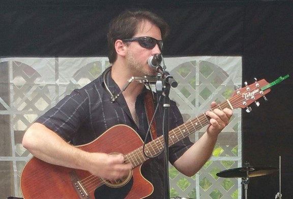Thomas Chamberlain performing with guitar and harmonica