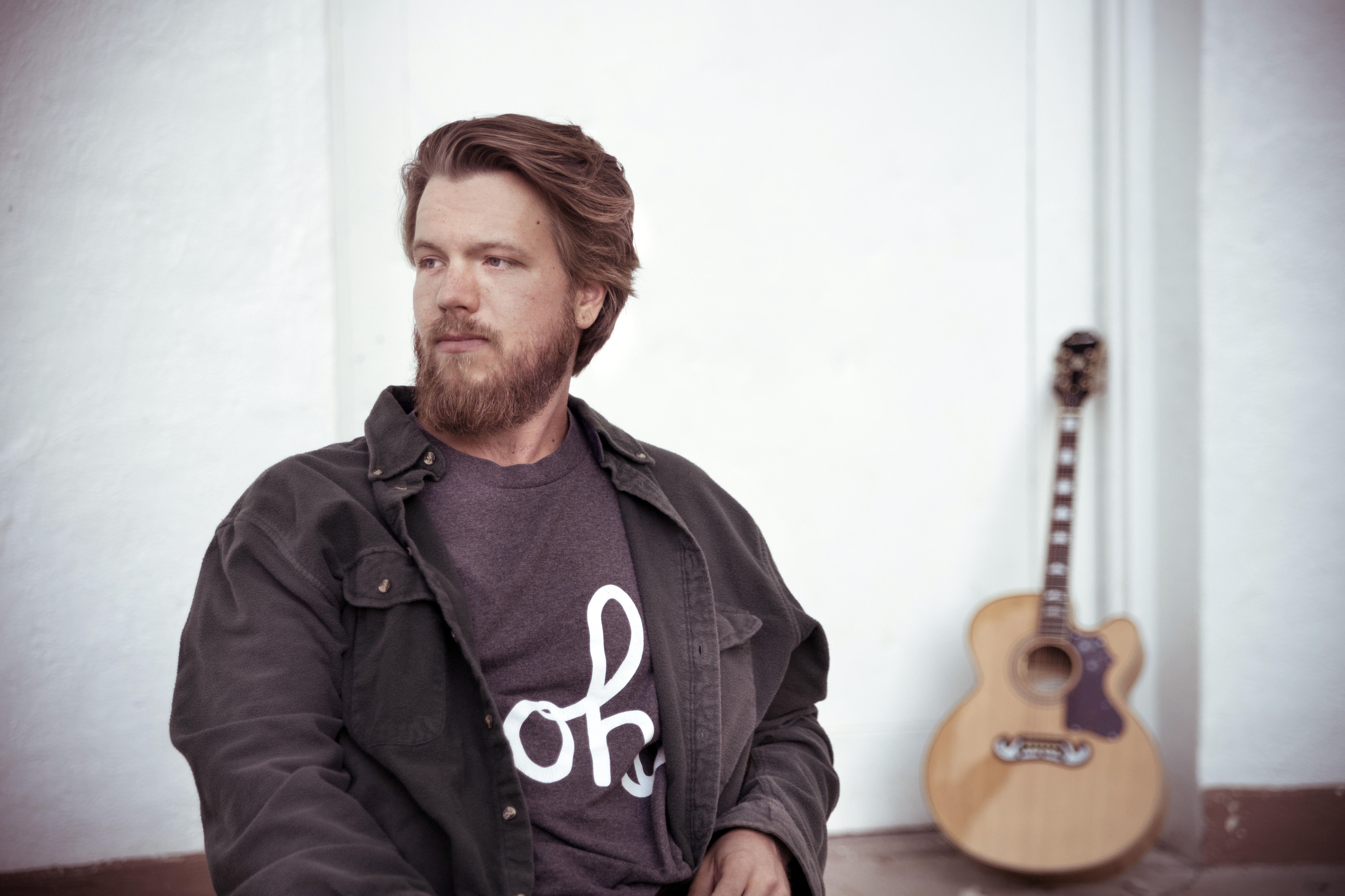 Portrait of Evan Meulemans with guitar in the background
