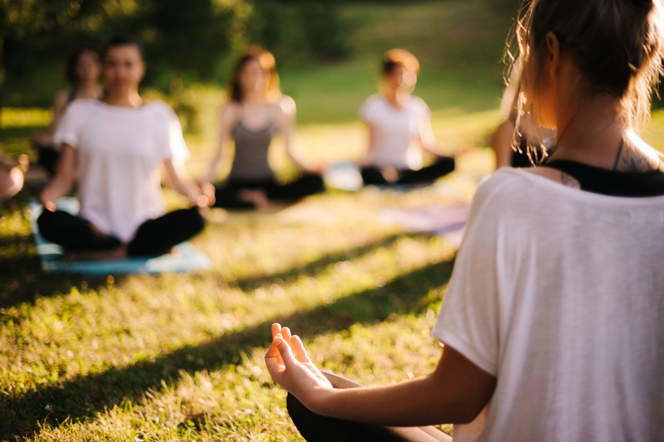 Image of women sitting in lotus position in grass.