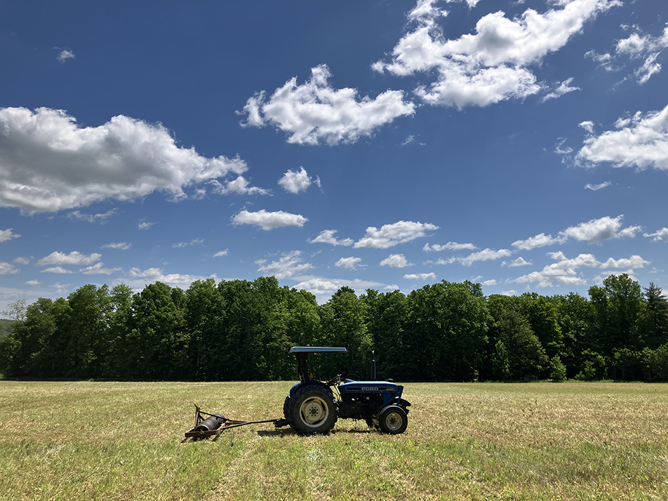Image of tractor in field under wide blue sky.