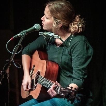 Laura Thurston performing with a guitar and harmonica