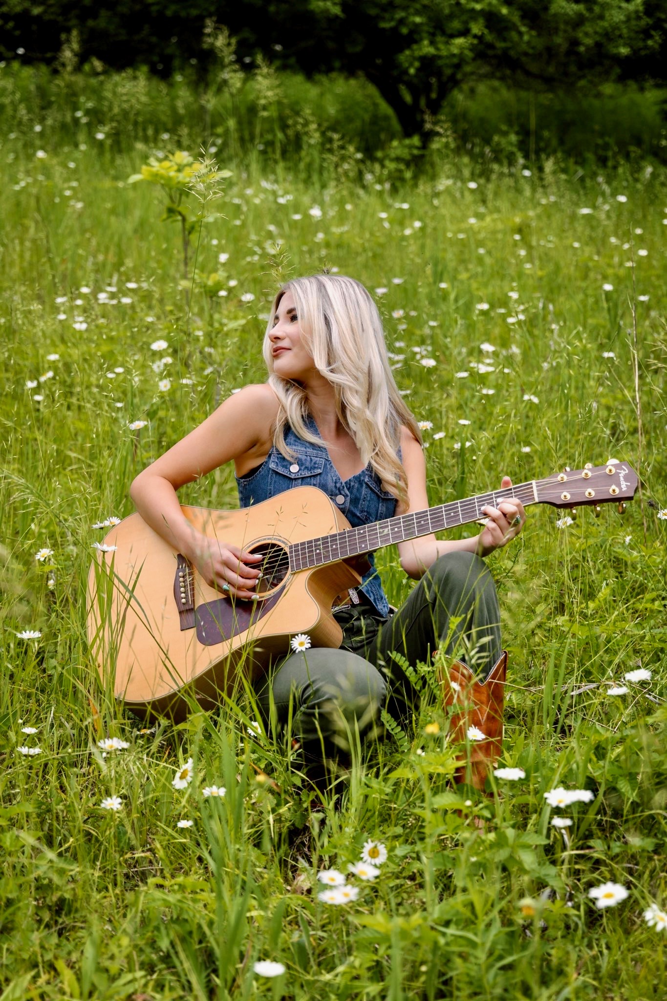 Portrait of Madelyn Rose in a meadow with her guitar