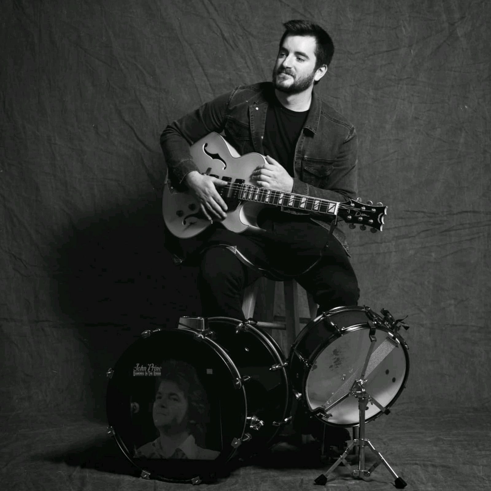 Portrait of Ryan Sutherland with drums and guitar