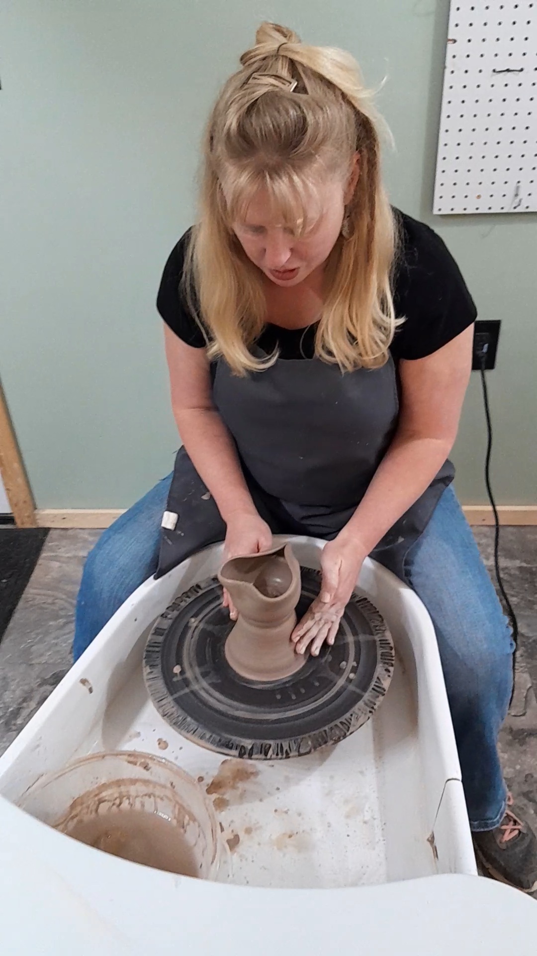 Beth Conway throwing clay on the wheel.